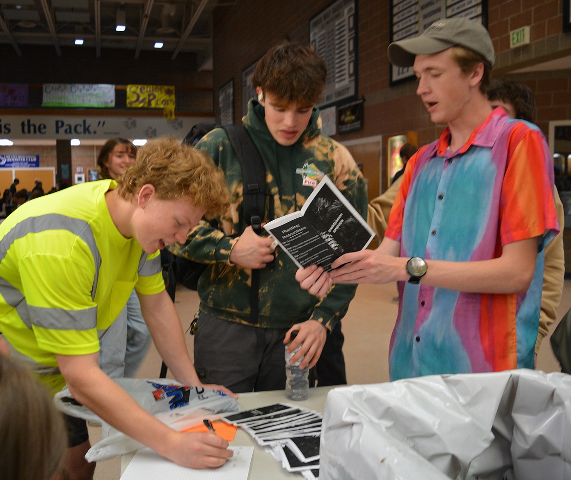 Rowen Lair fills out an order on the tree sale list as Nolan Jarvis and Ethan Stevens read about how to care for the Engelman spruce saplings. Lair is the junior class president and came up with the idea to sell saplings through student council to help improve the environment.