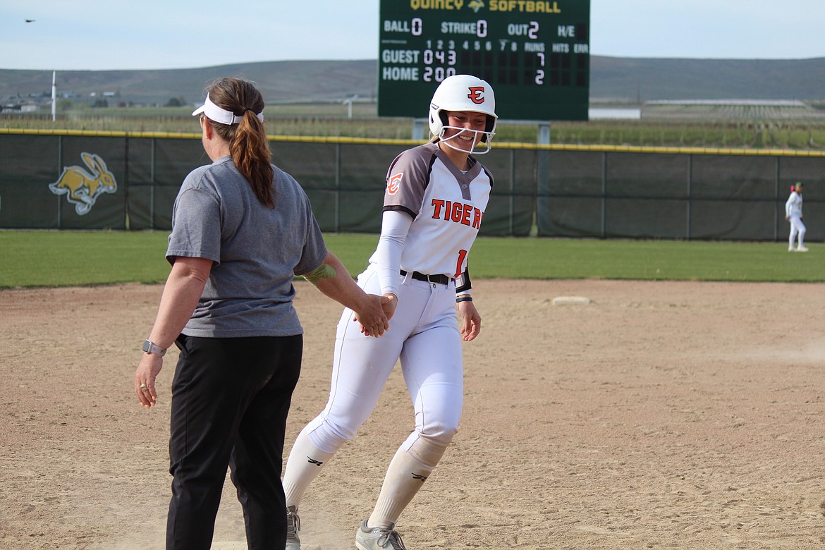 Dakota Durfee, right, gets a congratulatory handshake from Coach Heather Wood after hitting a two-run home run in the Tigers’ win over Quincy Tuesday.