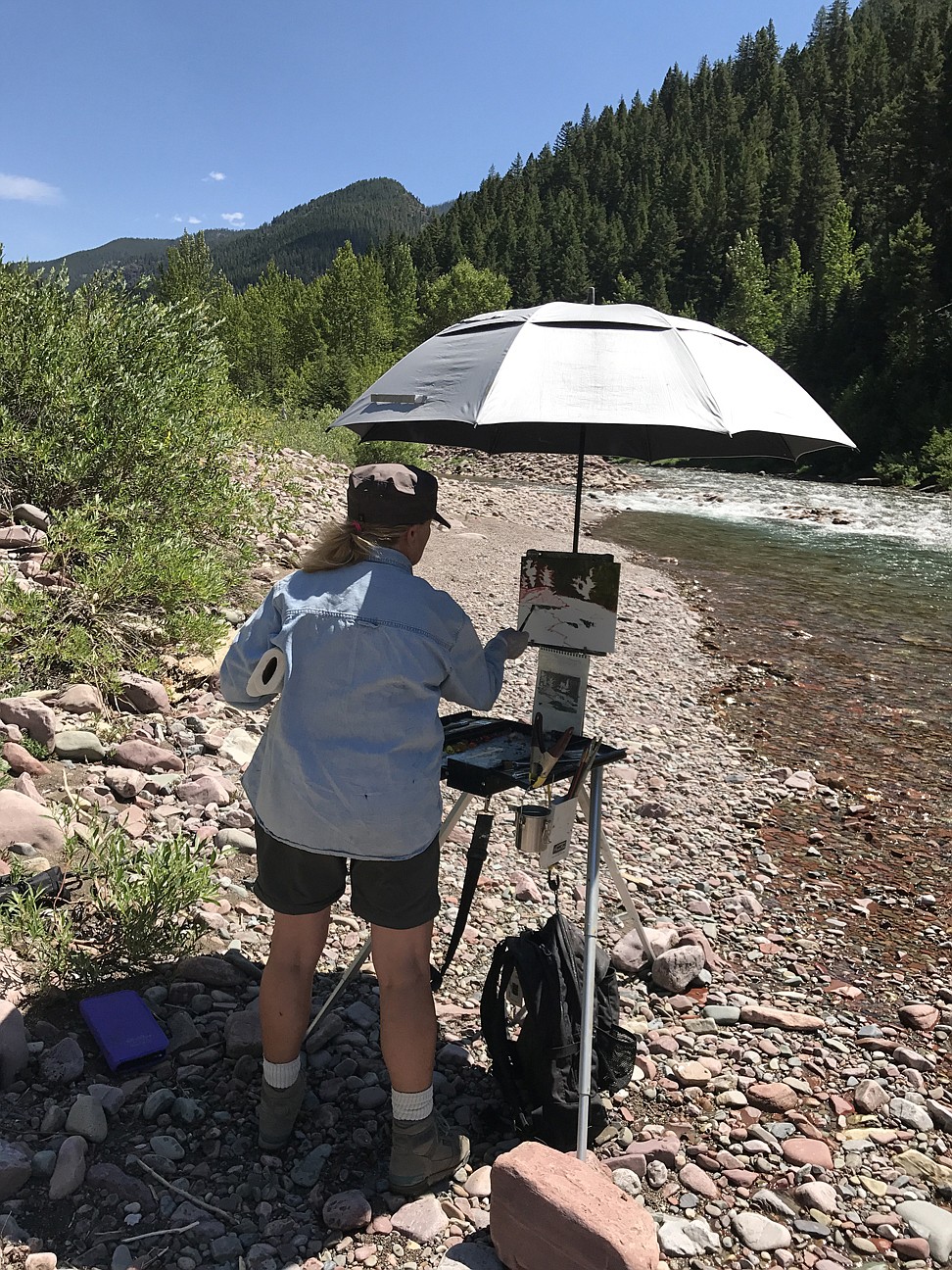 Gini Ogle, an artist who participated in the Artist Wilderness Connection resident program, paints outside of Granite Cabin in the Bob Marshall Wilderness. (Photo courtesy of Francesca Droll)