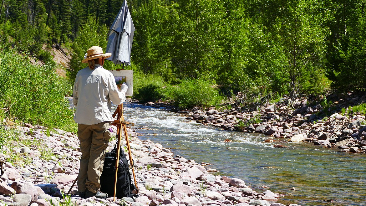 Francesca Droll stands with an easel in the Bob Marshall Wilderness. (Photo courtesy of Francesca Droll)