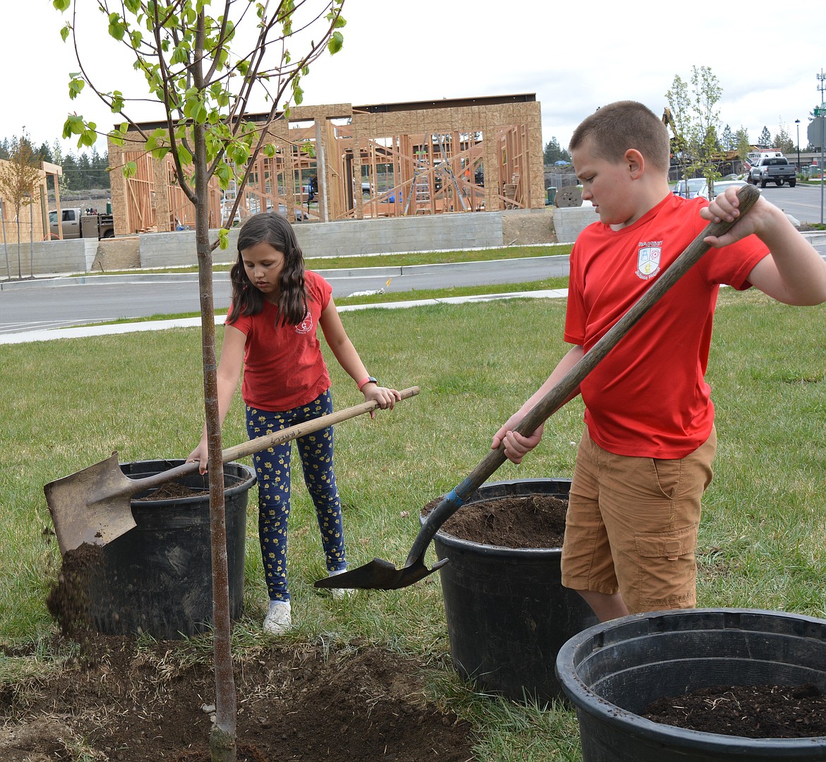 Ramsey Magnet School students Ruby Baker and Lane Churchill shovel dirt onto a new tree they helped plant during an Arbor Day celebration at Atlas Waterfront Park.