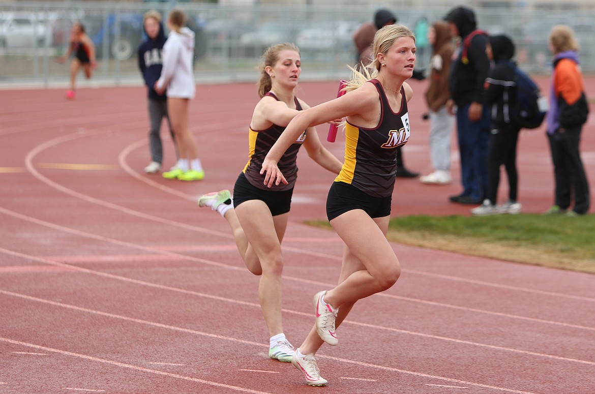 Moses Lake sophomore Reese Prescott, left, passes the baton to freshman Kamery Char, right, during the final leg of the girls 4x100-meter relay at Thursday’s meet.