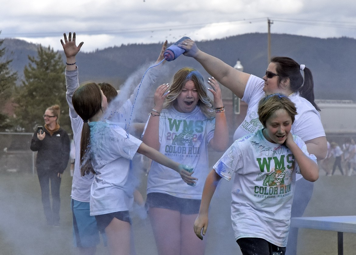 WMS student River Knudsvig throws her hands around in shock while Evalena Aurand gets doused in the face in blue. Around her, Riley Murphy, Wyatt Gemmill, Garek Bacon, Riley Bridgewater, Aiden Joy and Morgan Jenkins run past (Kelsey Evans/Pilot).