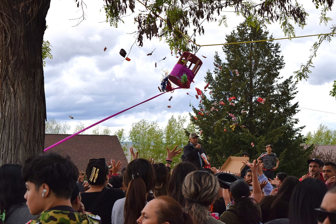 A Children’s Day event volunteer pulls a cord to spin candy from the piñata hanging in Hund Memorial Park Saturday as event attendees reach out to catch the flying candy.