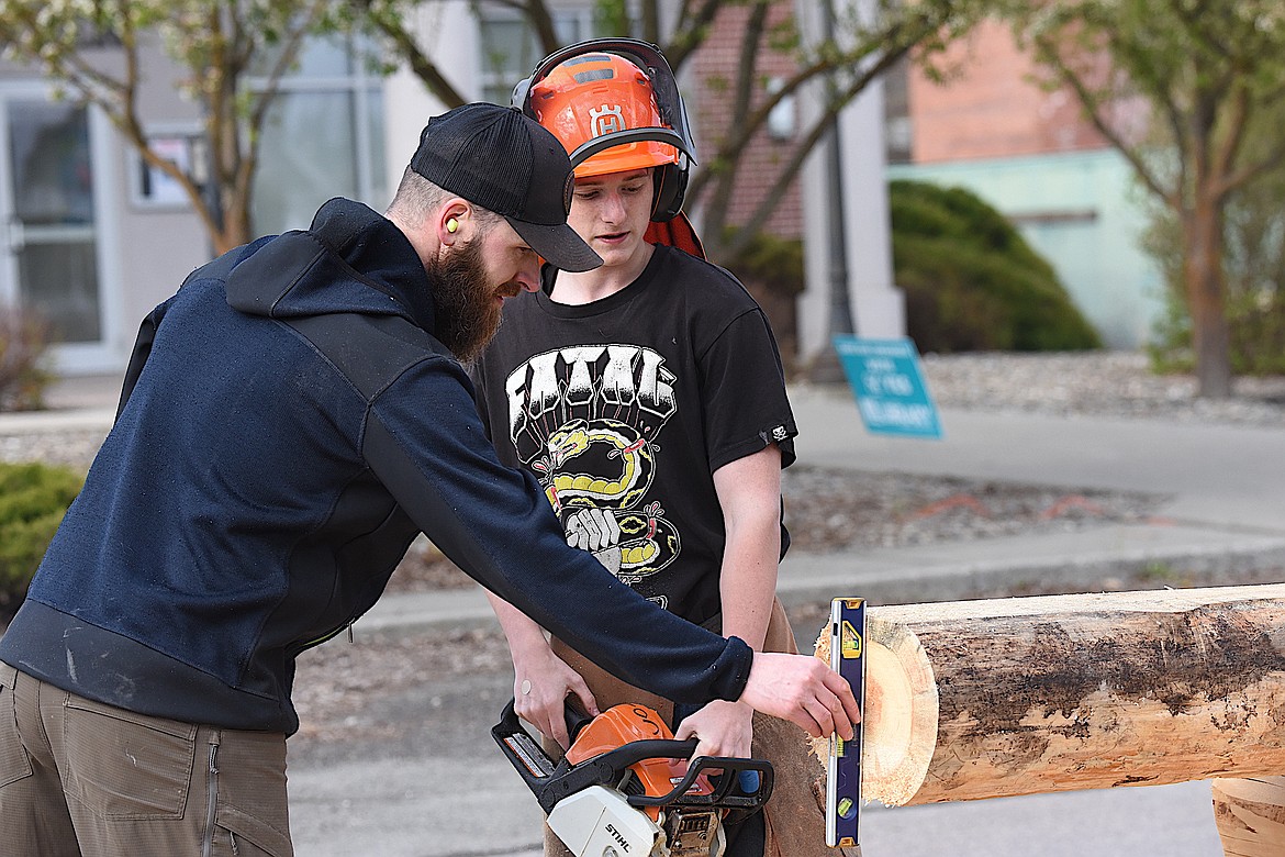 Meadowlark Log Home's Isaac Nelson checks a cut made by Libby High School student Tristan Hibbs on Tuesday, April 30, 2024, during the Workforce Expo in Libby. (Scott Shindledecker/The Western News)