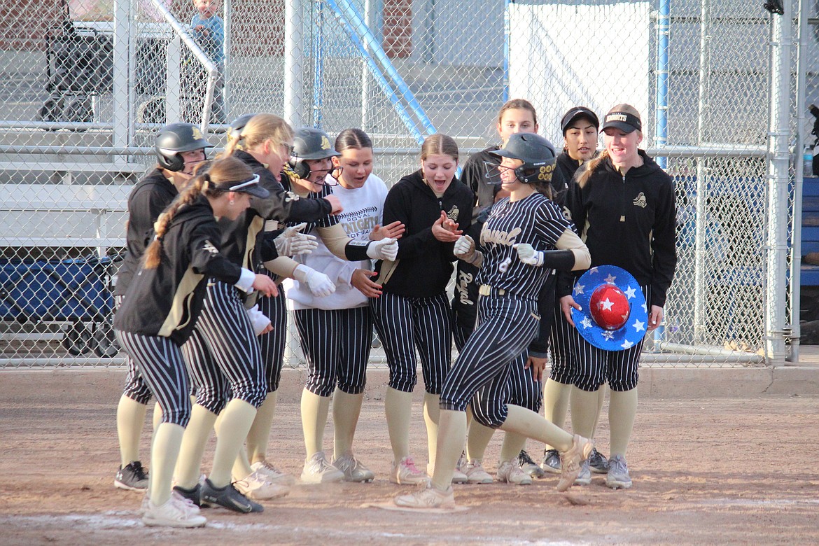 The Royal softball team gathers as JIll Allred (6)  crosses home plate after her solo home run against Warden.