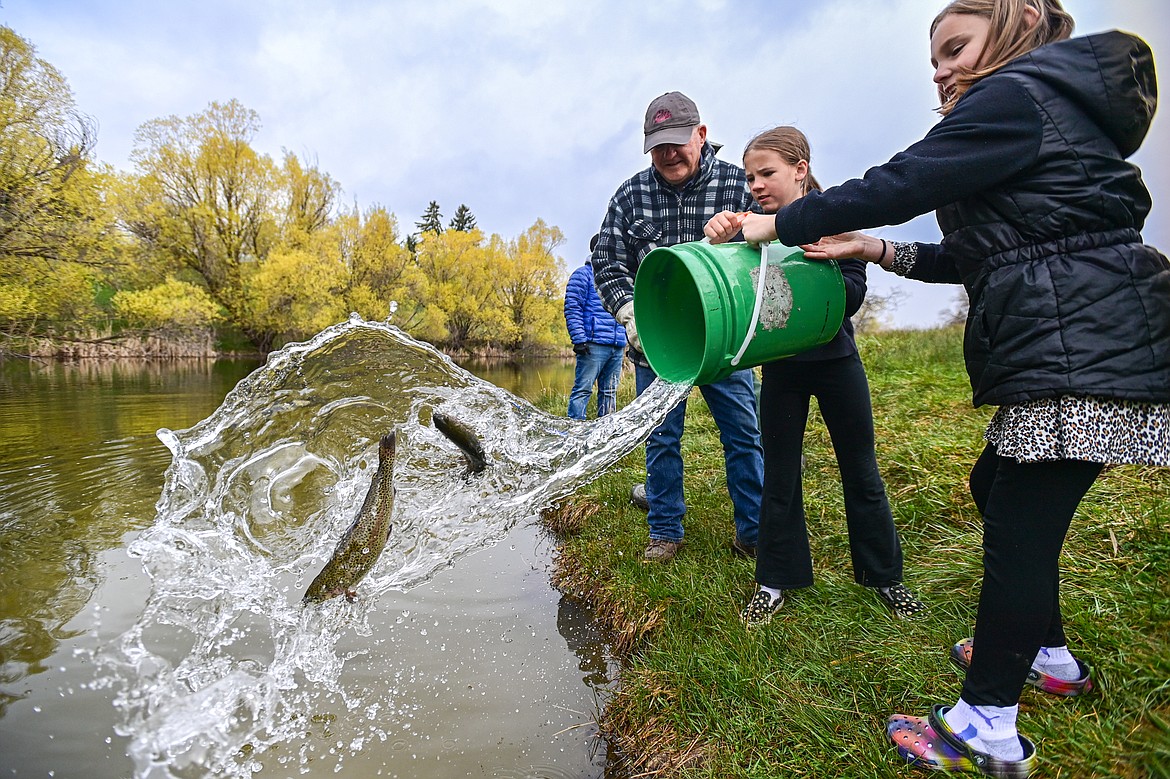 Hedges Elementary School fourth-graders Kinley Syckes and Oakley Solum pour a bucket of rainbow trout into the water at Dry Bridge Park during the Hooked on Fishing program held by Montana Fish, Wildlife and Parks on Thursday, May 2. (Casey Kreider/Daily Inter Lake)