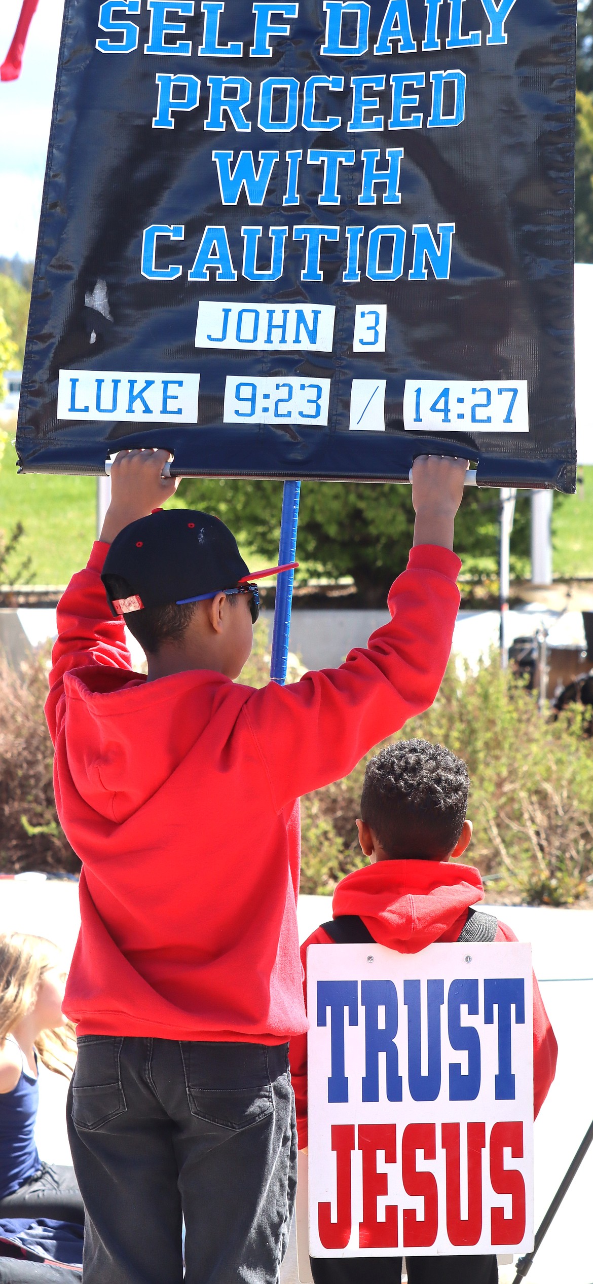 Two youth hold signs during the National Day of Prayer rally in Coeur d'Alene on Thursday.