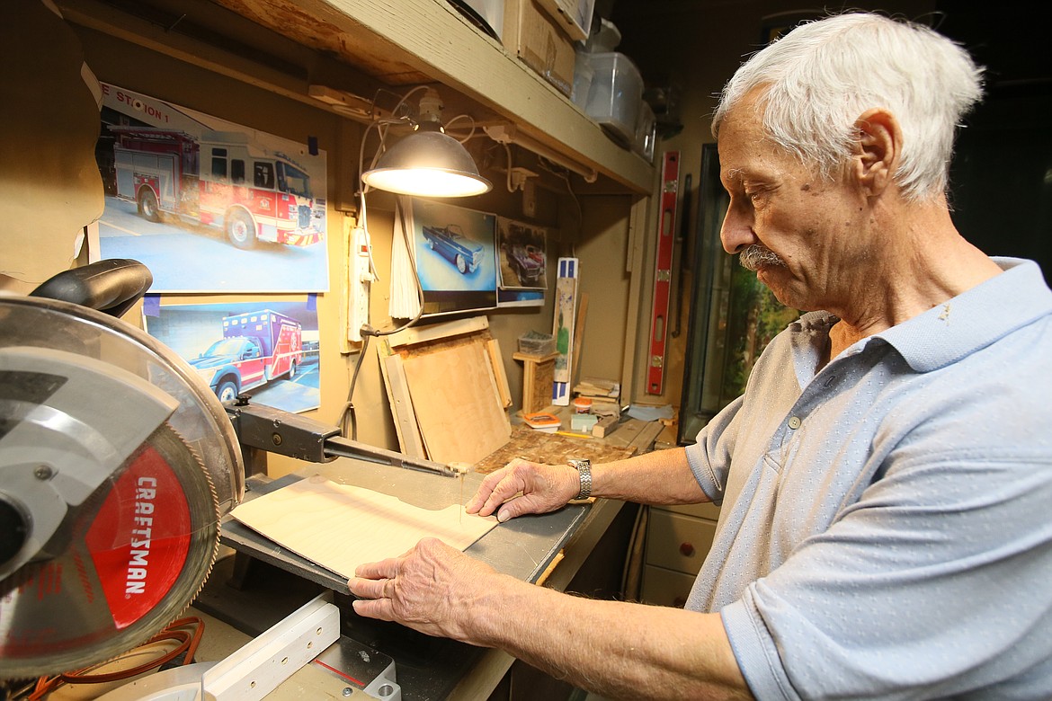 Tim Scarola of Post Falls demonstrates Friday how he cuts pieces of wood he then paints to create a 3D effect in many of his artistic creations.