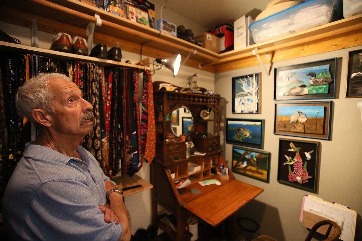 Post Falls artist Tim Scarola discusses his work Friday morning while showing his many unique creations hanging throughout his home, including in a walk-in closet.