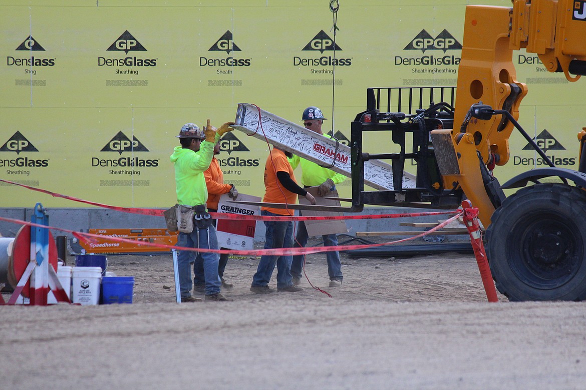 Construction workers get ready to lift the last piece of framing, covered with signatures of construction crews, Samaritan Healthcare employees and community members, into place.