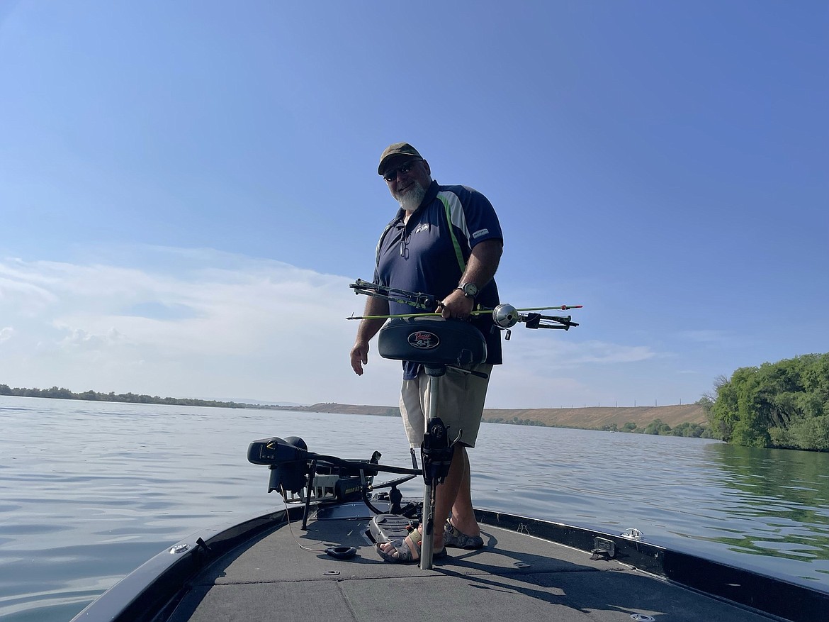 Moses Lake Carp Classic organizer Ty Swartout stands on the bow of his bass fishing boat and prepares to shoot carp as the boat drifts along the shore of Moses Lake at last year’s tournament. This year’s Carp Classic is May 18.