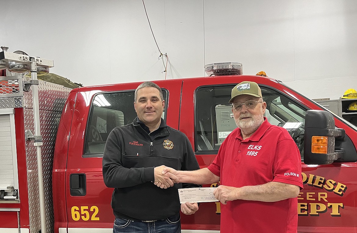 Joel Fuhrmann, chief of the Charlo-Moiese Fire Department, receives a check from Gail Nelson of the Mission Valley Elks Lodge.