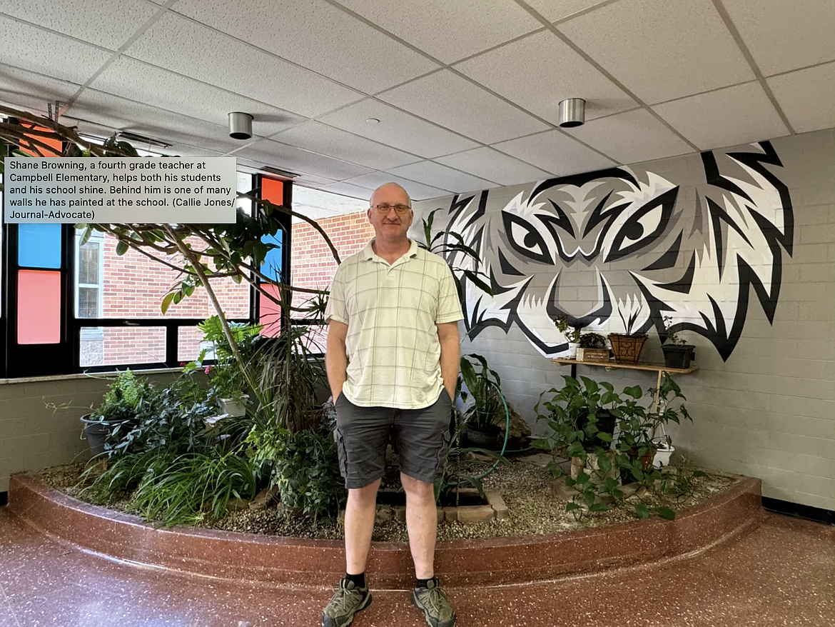 Shane Browning, a fourth grade teacher at Campbell Elementary, helps both his students and his school shine. Behind him is one of many walls he has painted at the school. (Callie Jones/Journal-Advocate)