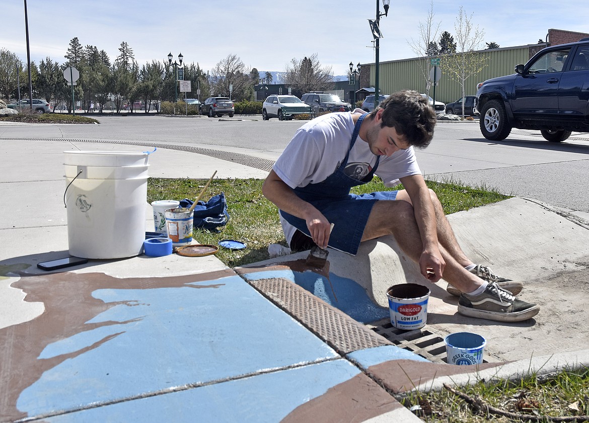 Elias Anderson begins to paint over the old mural (Kelsey Evans/Whitefish Pilot).
