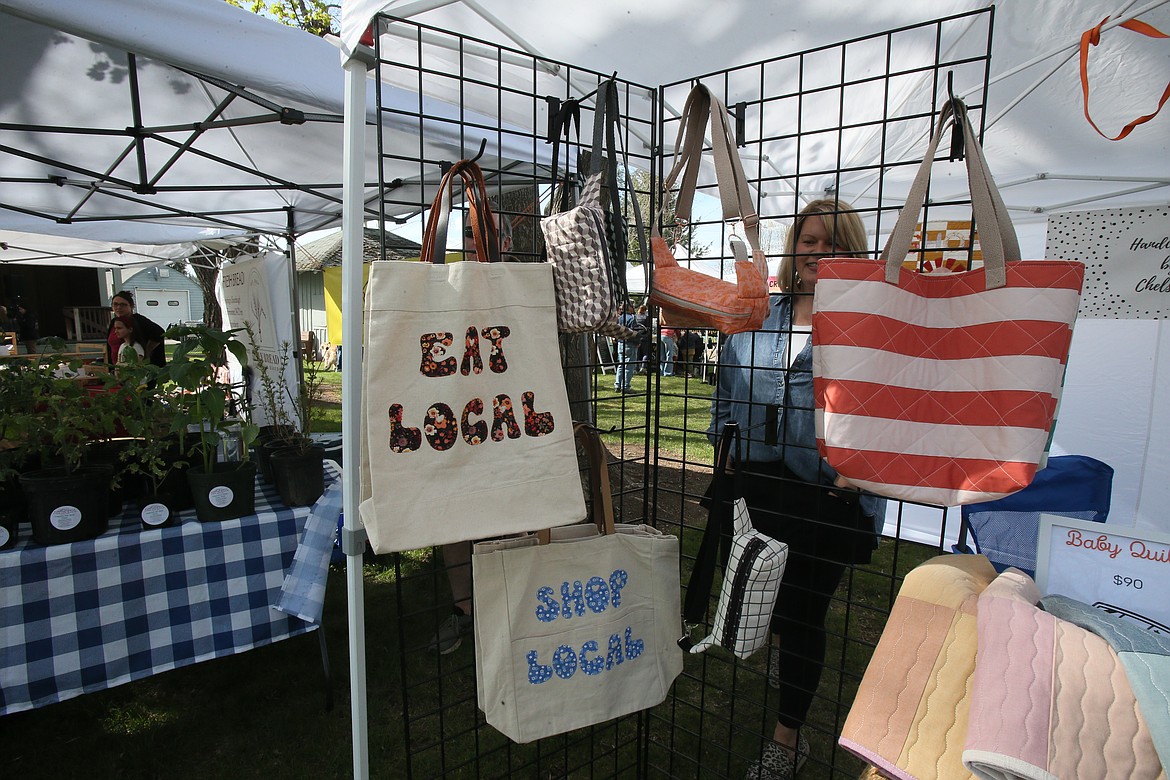 Chelsea Gottas peeks out from behind a display of her quilted creations at her Handcrafted by Chelsea booth Friday during opening day of the Athol Farmers Market.