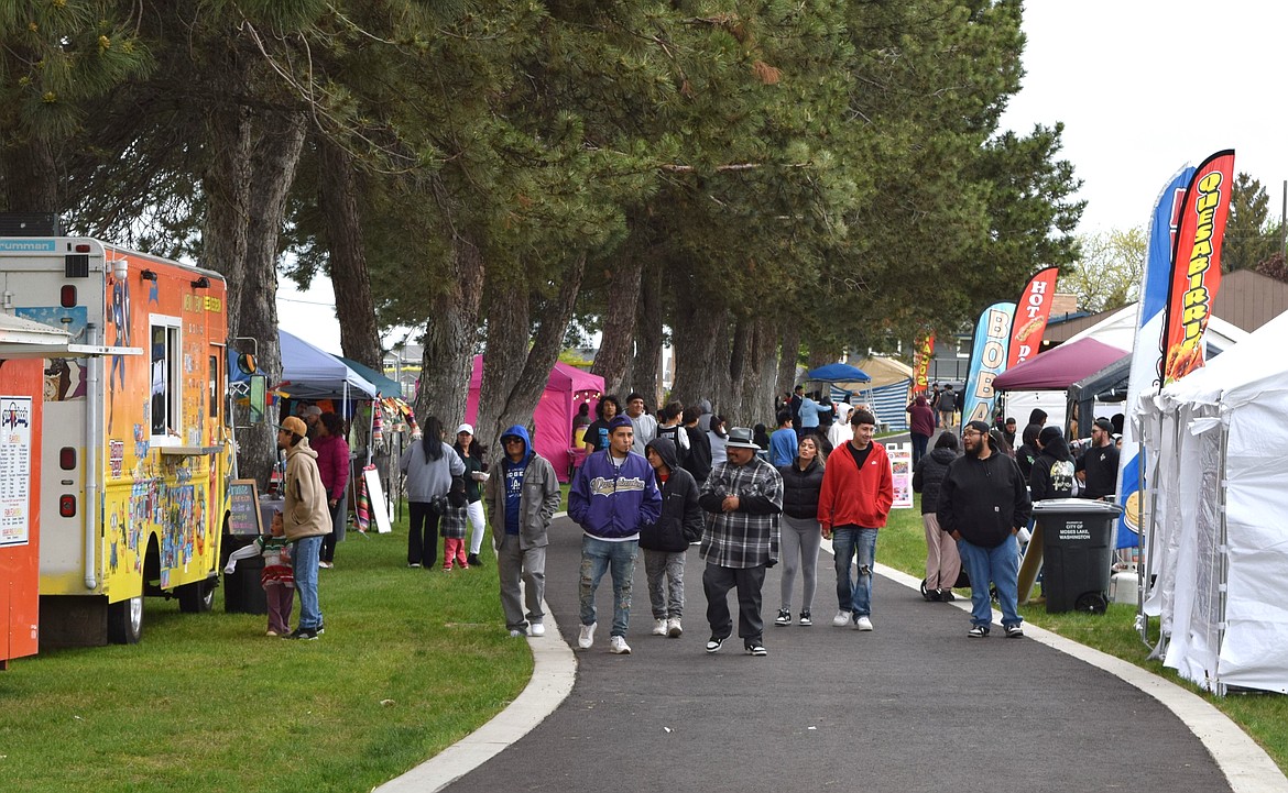 Cinco de Mayo event attendees walk down the pathway lined with food vendors at Lions Park Saturday afternoon.