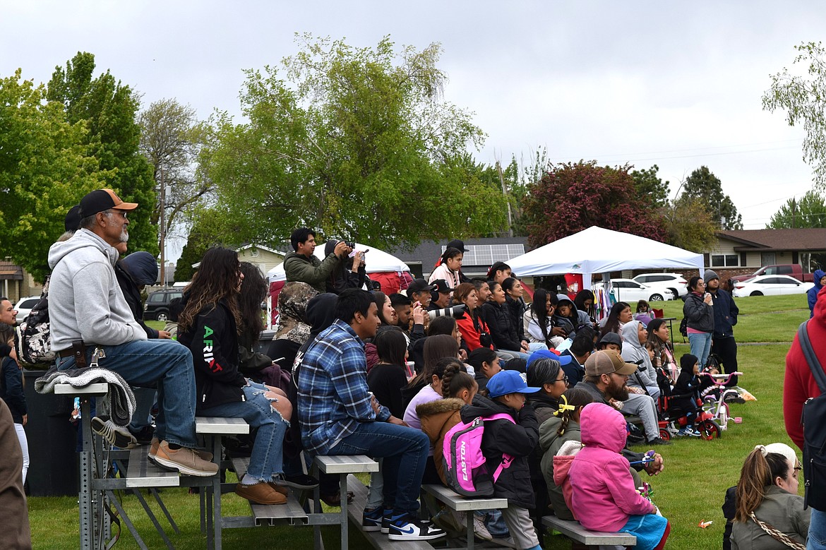 Attendees of Saturday’s Othello Cinco de Mayo event sit on bleachers in front of a stage in the center of Lions Park watching dancing performances, live music and other activities.