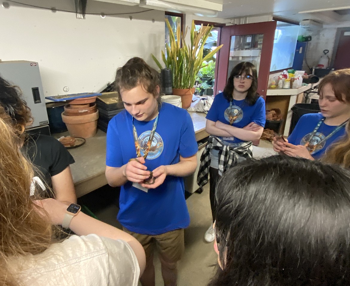 Coeur d'Alene High sophomore Oliver Arine, center, holds a rubber boa during a greenhouse tour while participating in a lunar flyby challenge held Friday and Saturday at Central Washington University. Students learned about plants that can be grown in harsh conditions, like the moon's surface