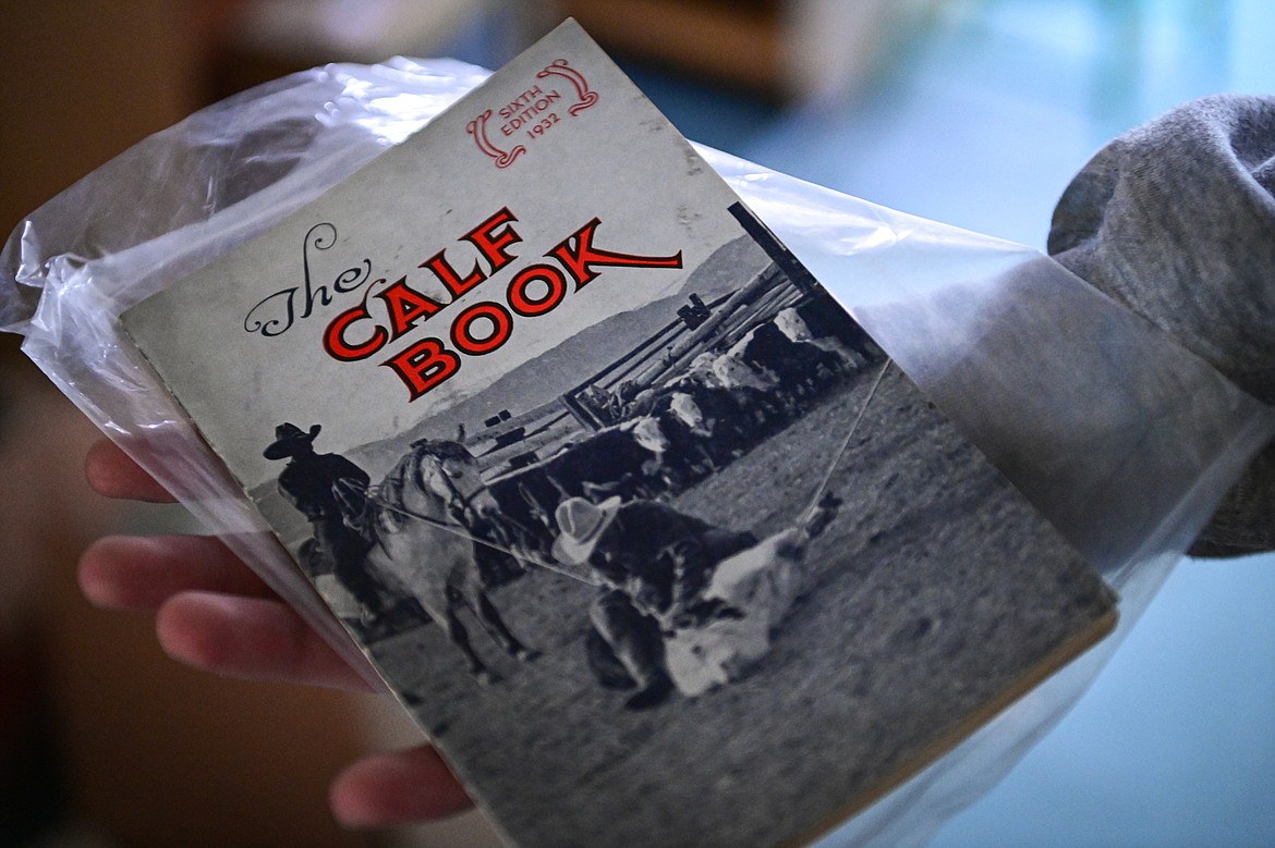 Aiden DeLong holds a 1932 edition of "The Calf Book," detailing how to raise livestock and avoid cholera, selling serums and compounds