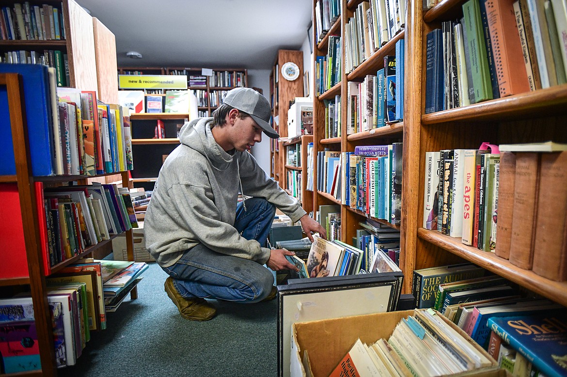 Aiden DeLong looks through a box of books at Parkland Books on Wednesday, May 8. (Casey Kreider/Daily Inter Lake)