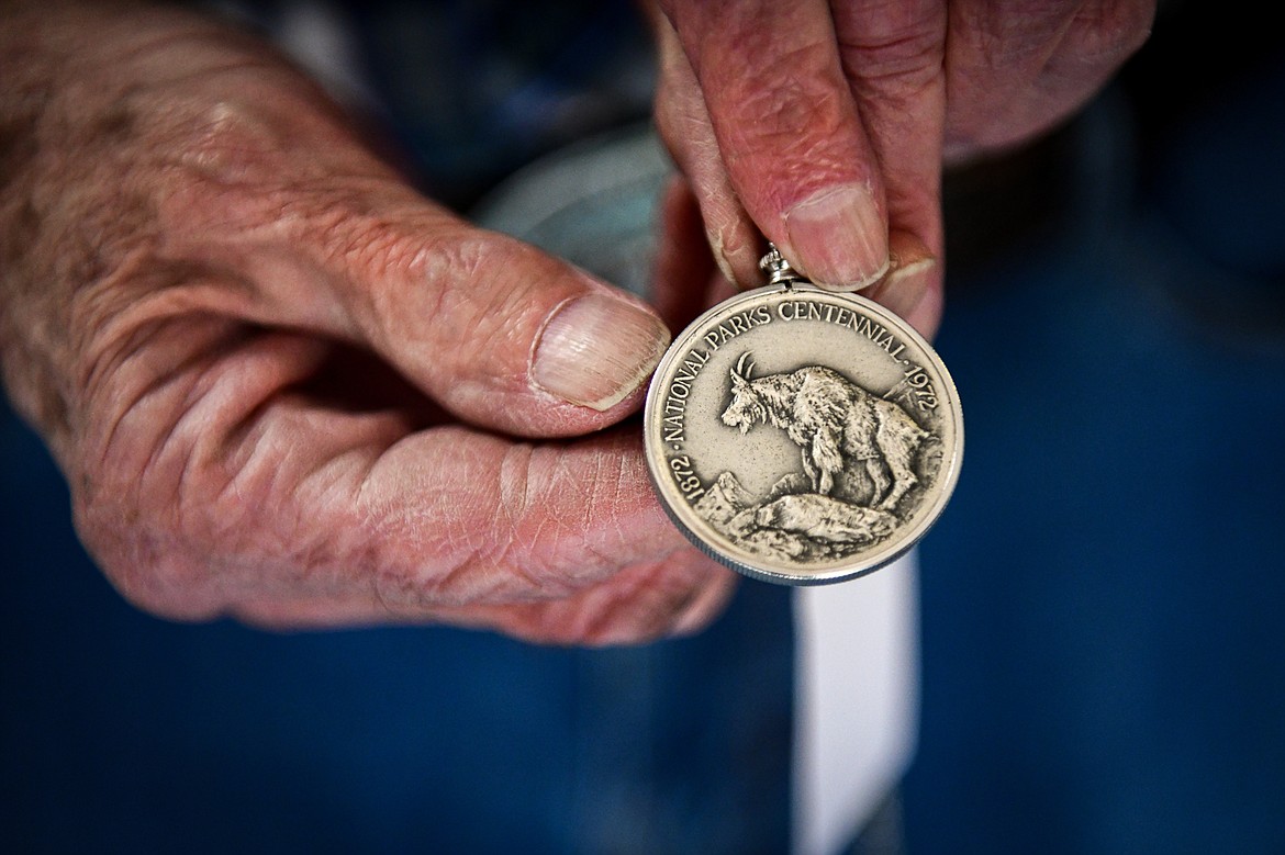 Ed Rothfuss shows a Glacier National Park silver medal made in 1972, part of a National Parks Centennial Medal Series, at Parkland Books on Wednesday, May 8. (Casey Kreider/Daily Inter Lake)