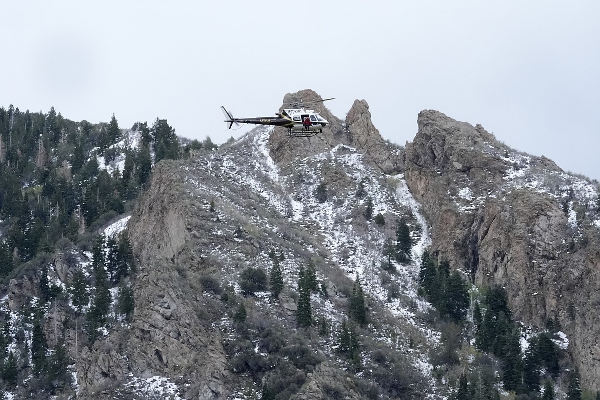 A Utah Department of Public Safety helicopter carries rescuers from Hidden Valley Park on Thursday in Sandy, Utah. One skier was rescued and two remained missing following an avalanche in the mountains outside of Salt Lake City. The slide happened after several days of spring snowstorms. (AP Photo/Rick Bowmer)