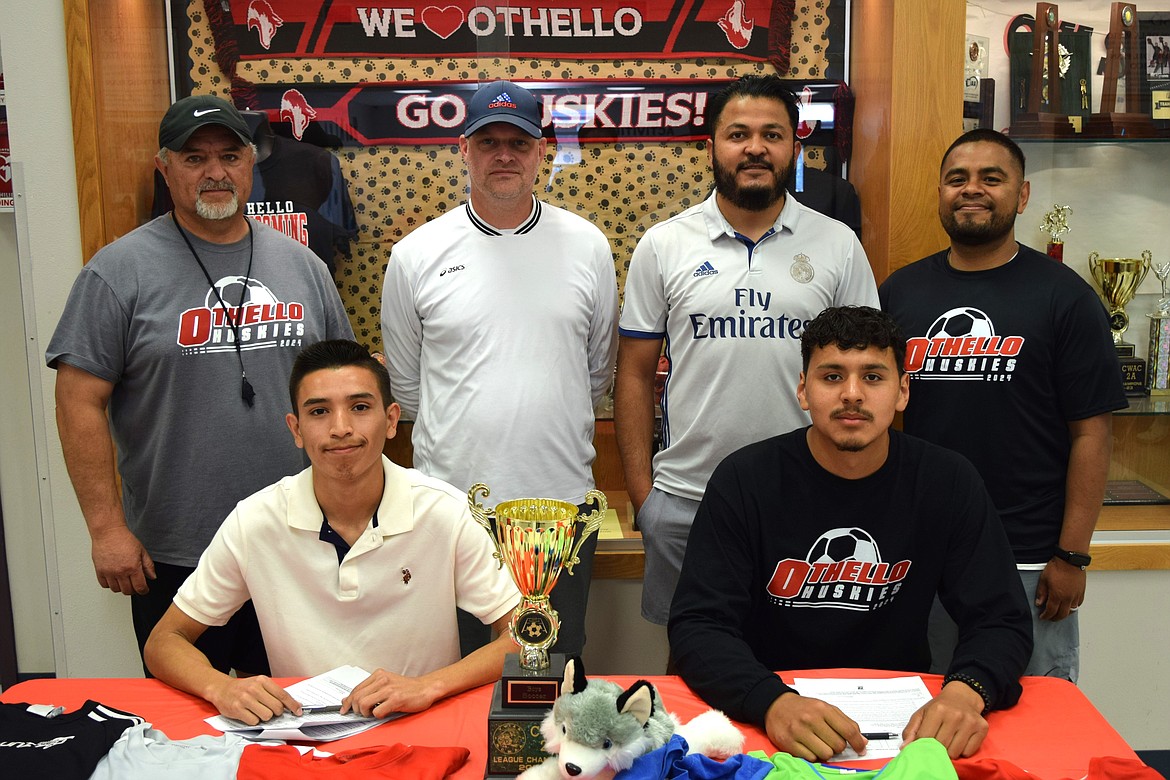 Othello High School Soccer players Felipe Haro, sitting left, and Don Eldred, sitting right, prepare to sign their national letters of intent to play college soccer at Wenatchee Valley College Wednesday evening with the team’s coaching staff, standing.