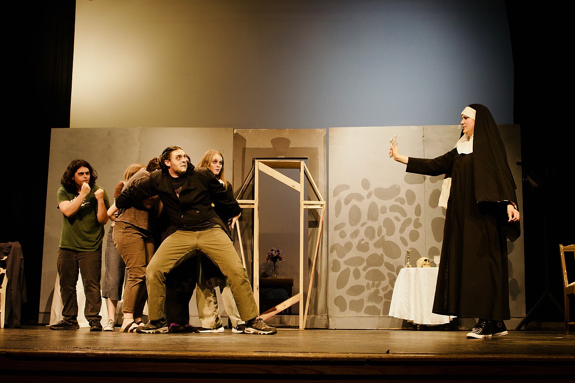 Lake City High School senior Evelyn Bennett, dressed as a nun, holds up a cross as senior Ben Crespo restrains a group of his vampiric minions during rehearsal for "Silent, but Deadly." To Crespo's right is sophomore Kelsi Calderwood and on his left, junior Conner Moll raises his fists.