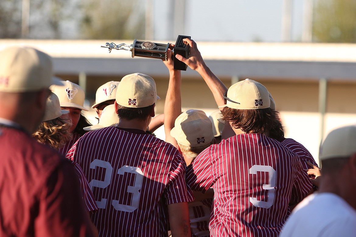 A Moses Lake player holds up the district championship trophy amid a celebration with teammates after the Mavericks defeated Eastmont 8-2 in the Columbia Basin Big 9 district championship game.