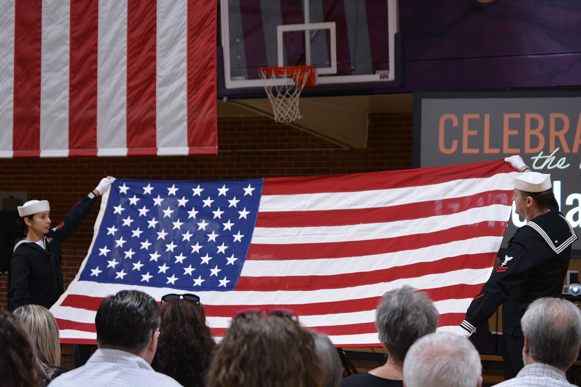 Et1  Joseline Gomez-Lopez and Hm2 Faton Sadiku unveil the American flag as part of the military honors for Gene Jacobs.