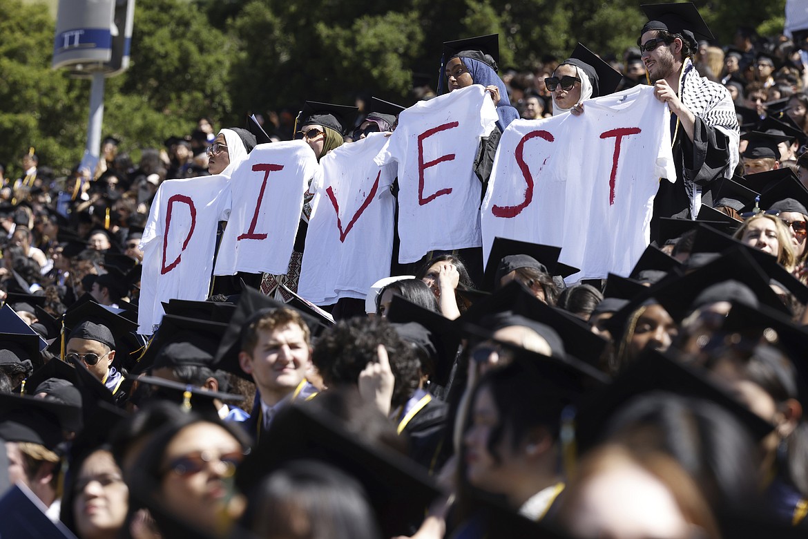 Pro-Palestinian students hold white t-shirts stating the message, "DIVEST," as they protest during the UC Berkeley graduation at California Memorial Stadium in Berkeley, Calif., on Saturday, May 11, 2024. (Yalonda M. James/San Francisco Chronicle via AP)