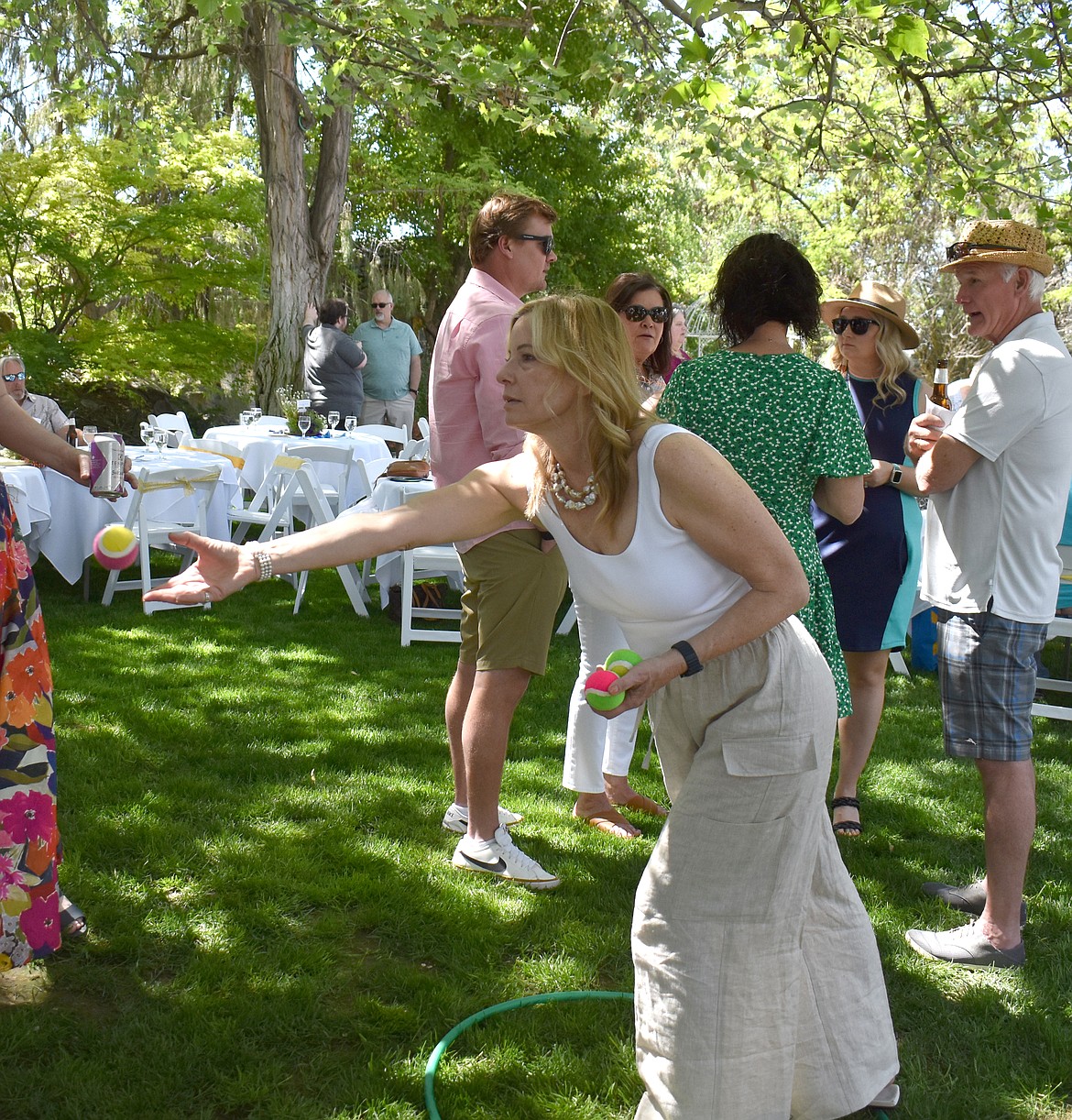 Columbia Basin Allied Arts board member Leslie Ramsden tosses a velcro ball at a target for a chance at a drawing to win a diamond bracelet at the CBAA Garden Party Saturday.