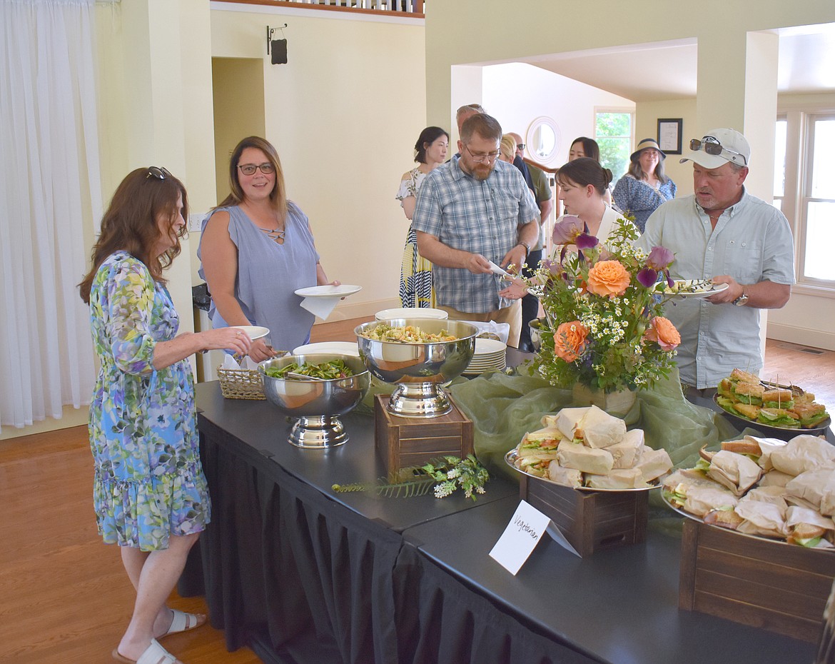 Attendees at the Columbia Basin Allied Arts Garden Party Saturday serve up sandwiches and salad catered by the Cow Path Bakery in Othello.