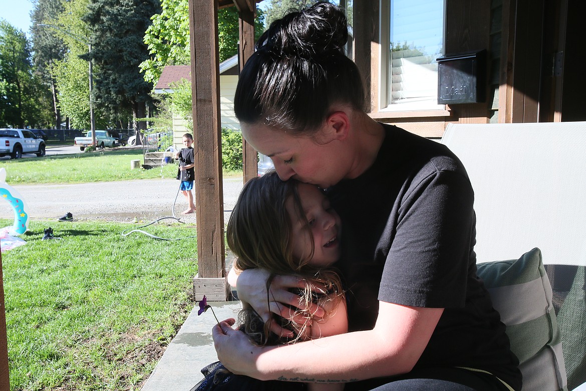 Heather Bischof plants a kiss on the forehead of her 5-year-old daughter Ellie as son Austin, 7, plays in the water on a summerlike May 9 evening.