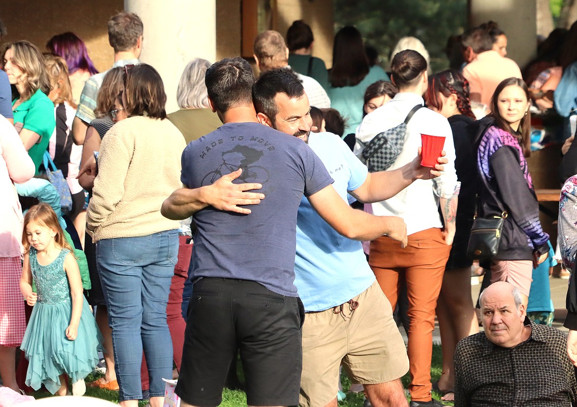 Adam Schluter shares a hug with a friend at the season's first Monday Night Dinner at McEuen Park.