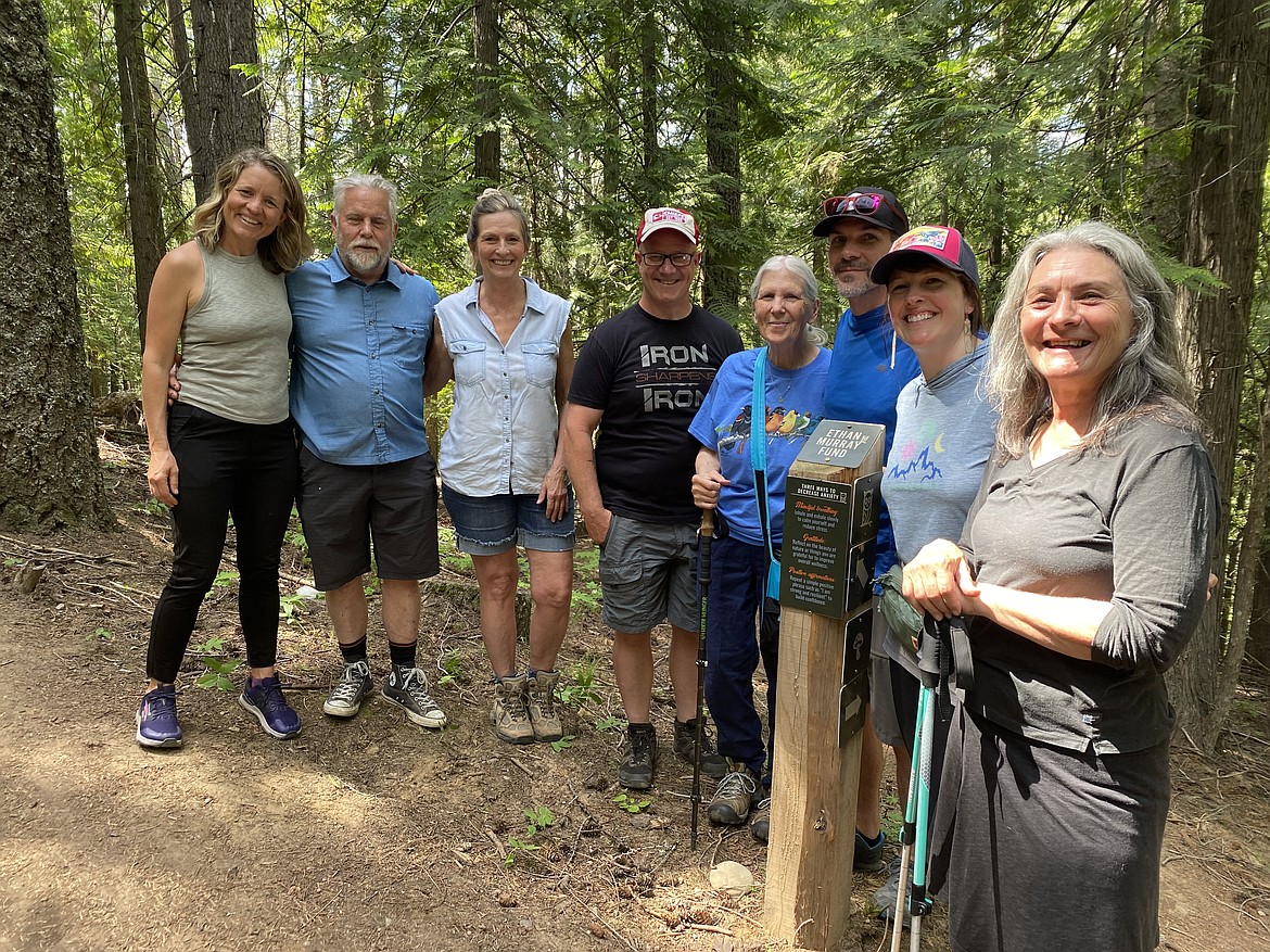 Kaniksu Land Trust staff and Ethan Murray Fund board members are pictured by a trail post on Pine Street Wood's Owl Trail that features a trailside mental health message.