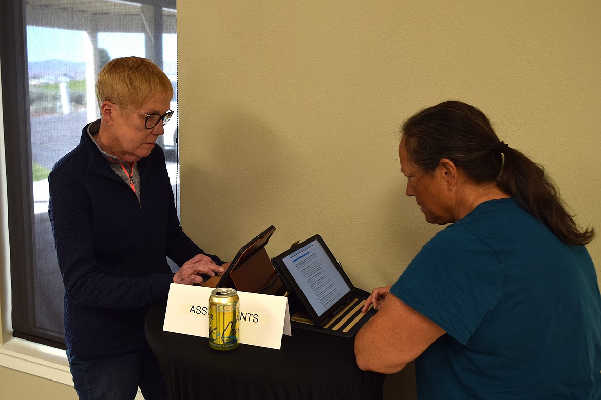 Desert Aire residents Kathryn Apolito, left, and Susie Miller, right, sign up for home visits Wednesday as part of the Washington Department of Natural Resources’ Wildfire Ready Neighbors program.