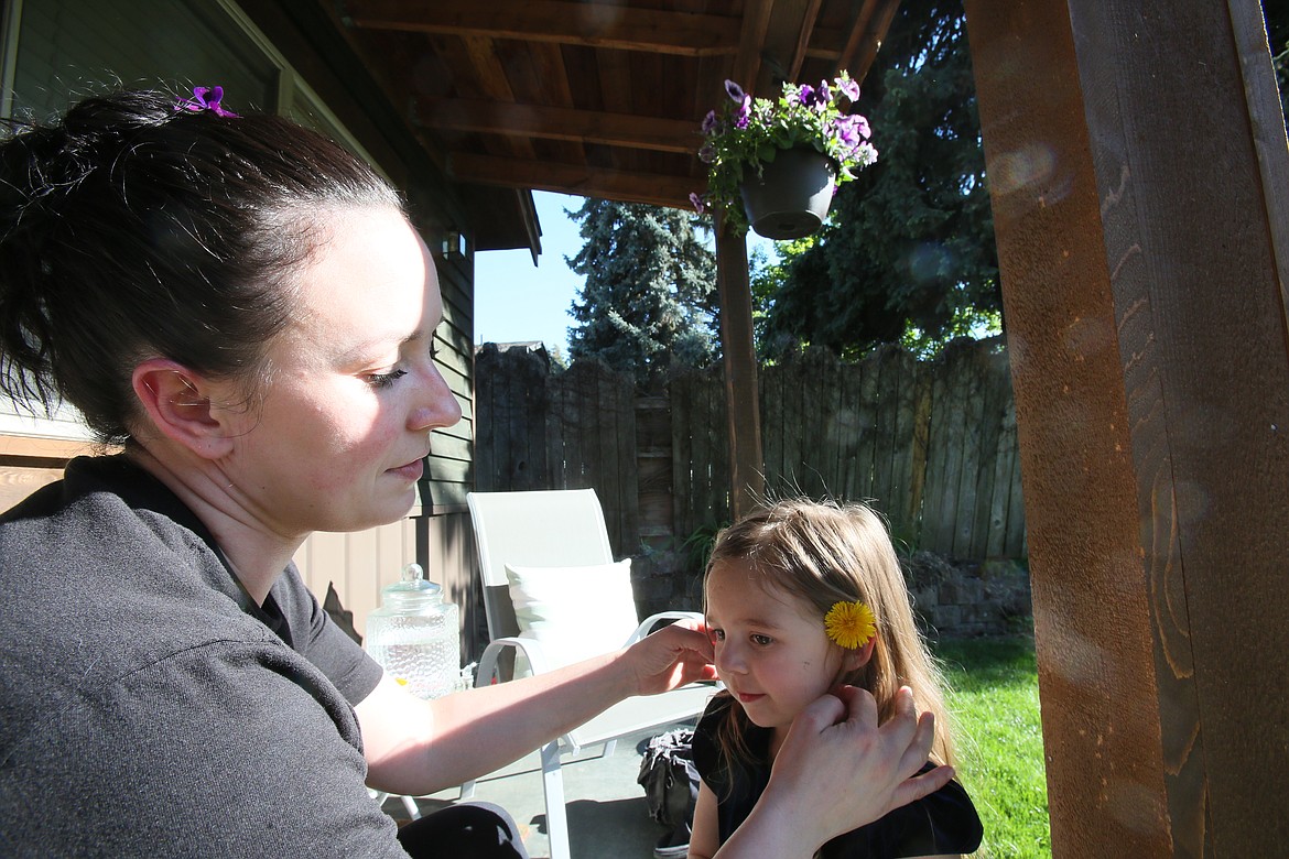 Heather Bischof places a flower behind her daughter Ellie's ear May 9 as they enjoy the sunshine on the front porch.