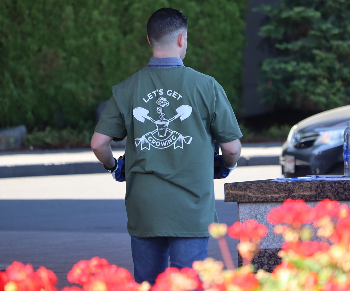 Zach Hoynes carries geraniums as he wears one of the shirts with the words, "Let's Get Growing" at The Coeur d'Alene Resort on Tuesday.