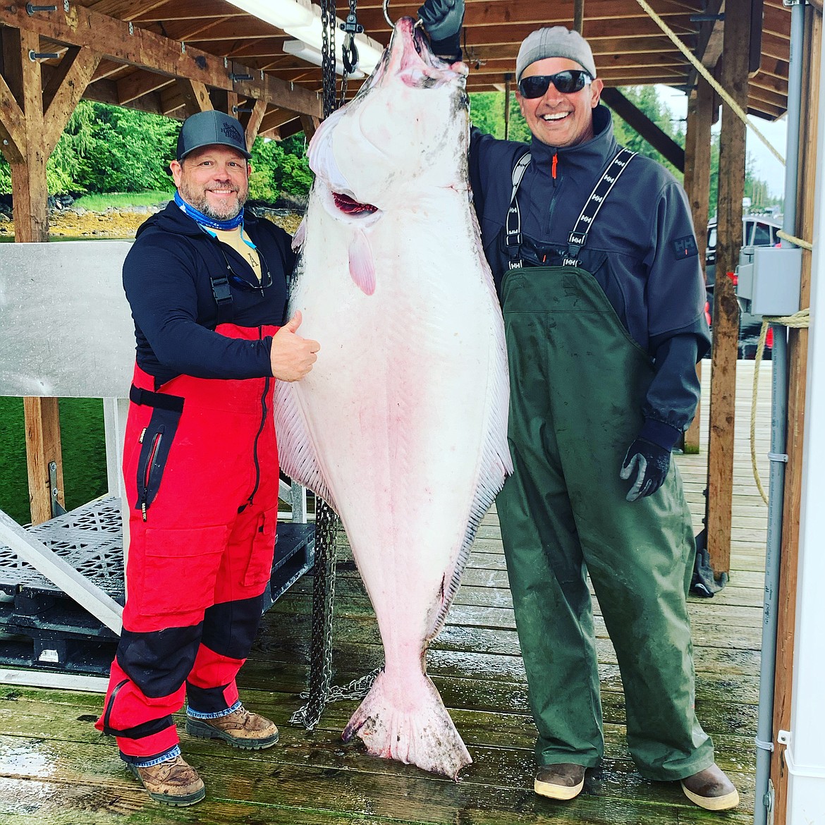 Mike Bunker and a friend stand by a giant halibut in Alaska.