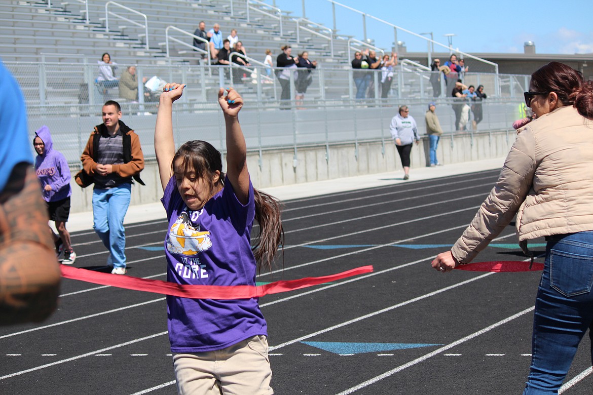 A runner crosses the finish line in triumph at the annual Field Day in Quincy Friday.