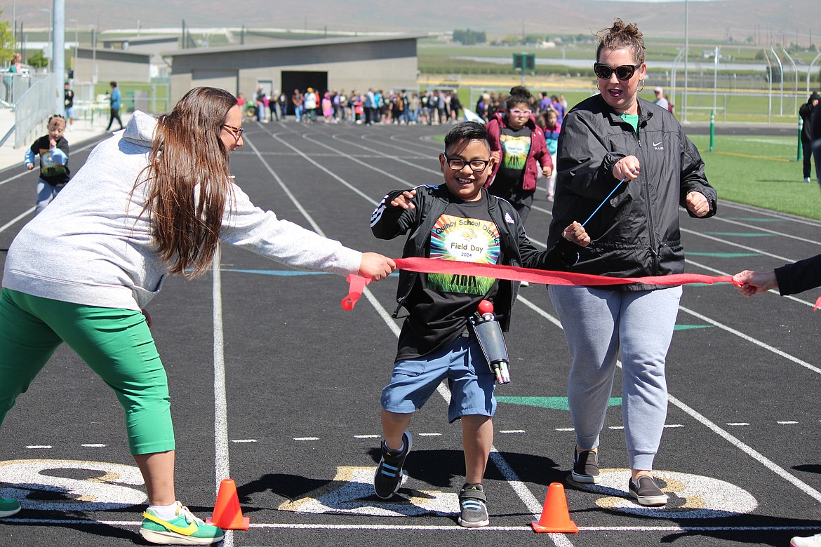 A runner happily breaks the tape at Field Day Friday.