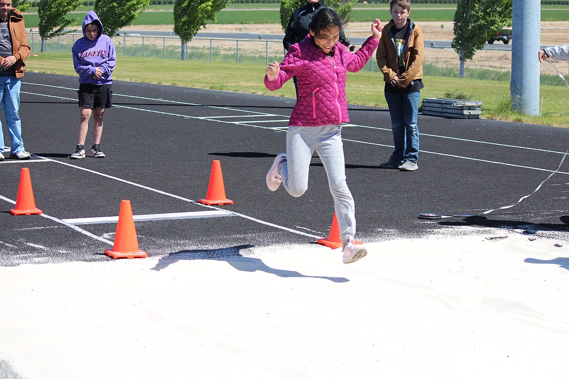 Field Day participants jump into the long jump pit.