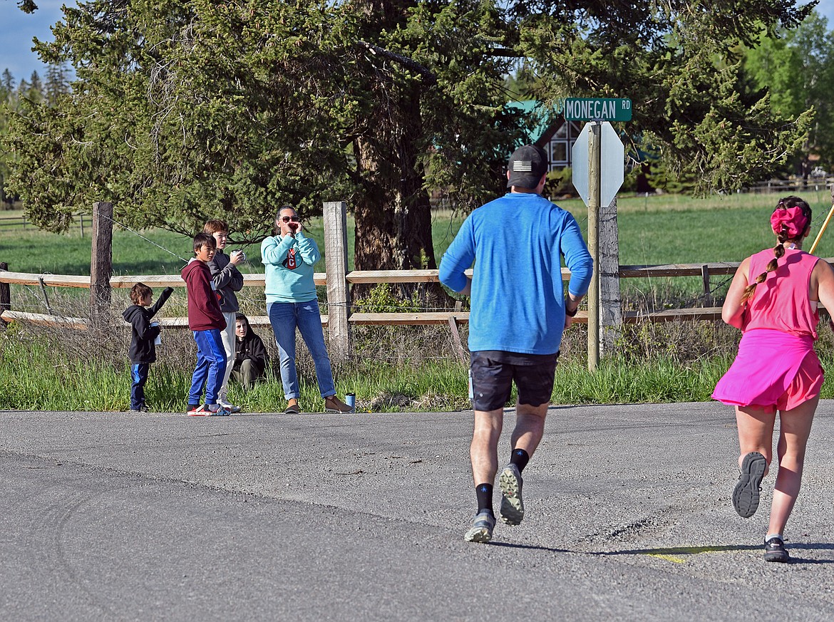 A race volunteer cheers on racers as the take the turn from Dillon to Monegan Road during the Whitefish Marathon May 18, 2024. (Julie Engler/Whitefish Pilot)