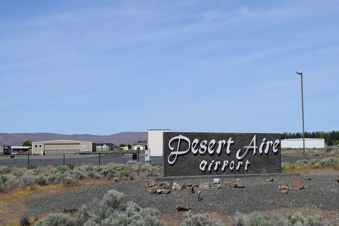 A sign marks the entry to the Desert Aire Airport. Surrounding the runway are numerous private properties with direct access to the tarmac.