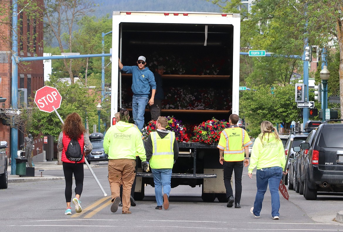 Volunteer follow the Aspen Nursery truck down Lakeside Avenue as they set flower baskets on light posts in downtown Coeur d'Alene on Tuesday.