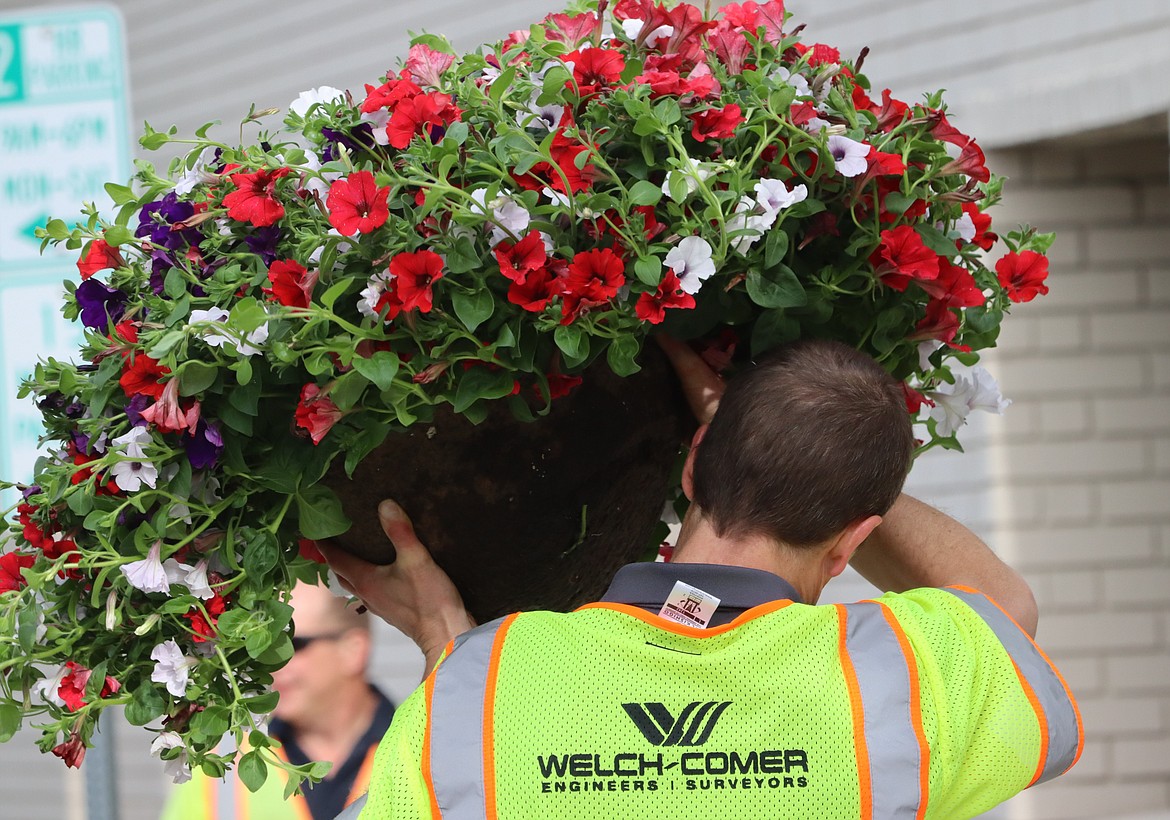 Matt Gillis with Welch Comer & Associates, Inc. carries a flower basket on Lakeside Avenue on Tuesday.