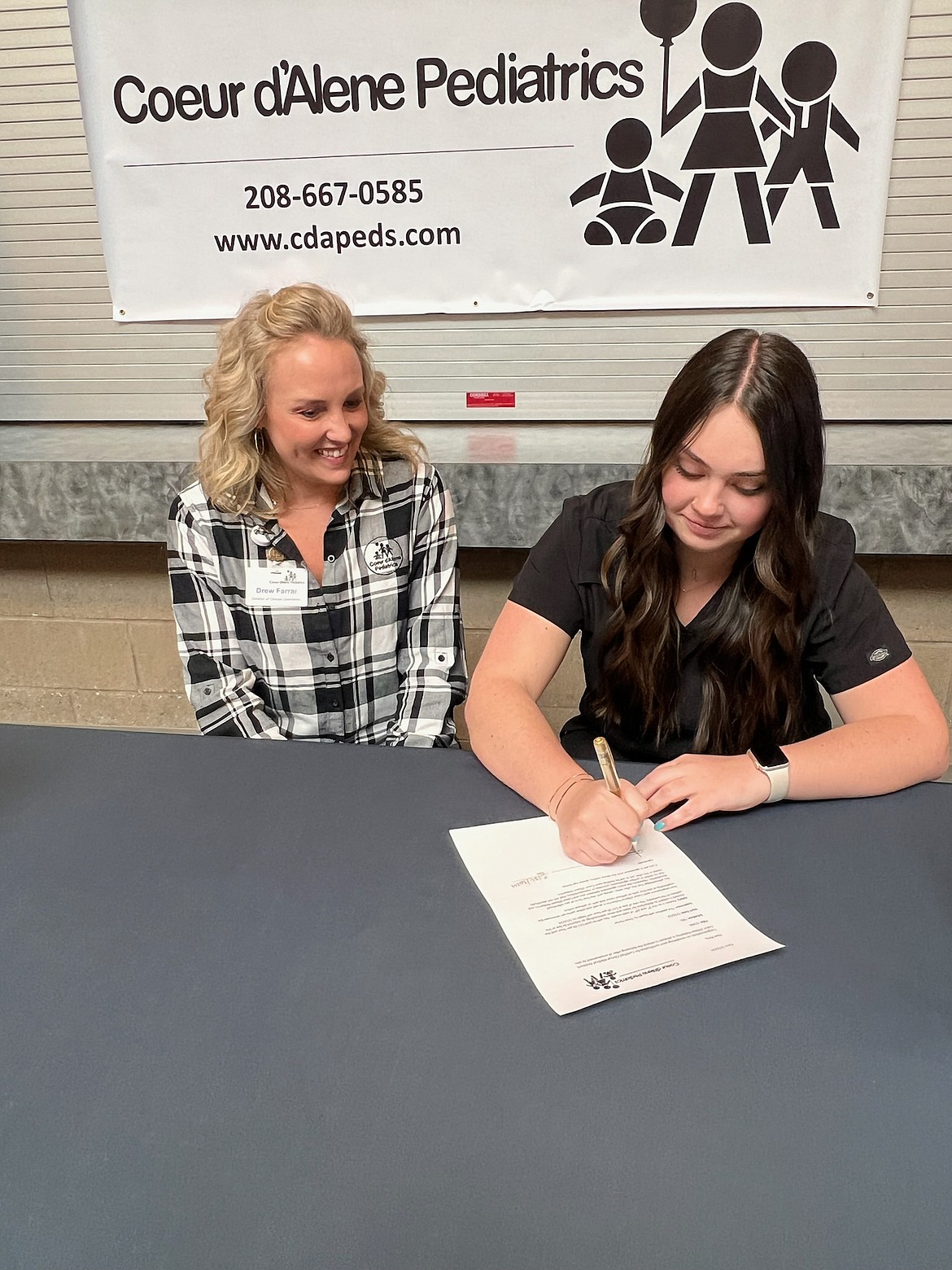 Drew Farrar, left, representing Coeur d'Alene Pediatrics, witnesses KTEC and Lake City High senior Riley Smalley sign on with the practice Wednesday during KTEC's signing day.