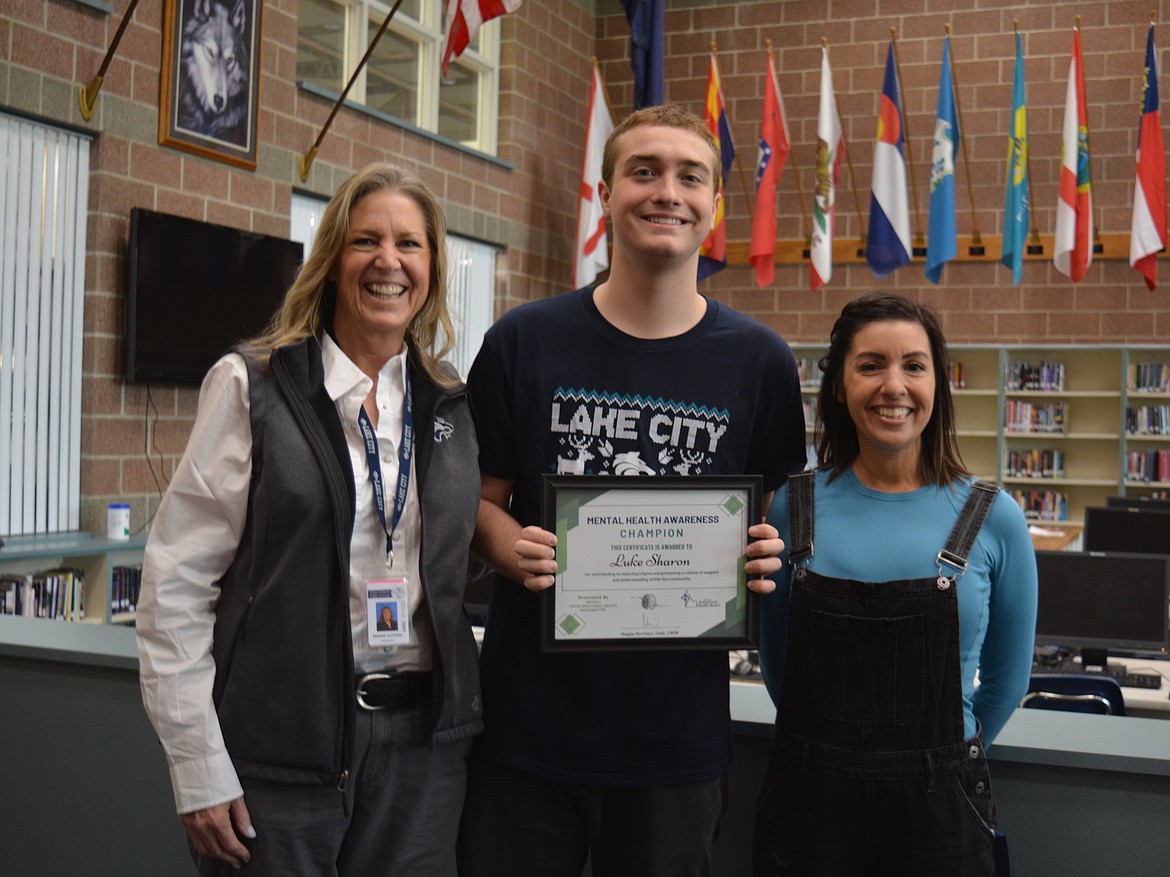 Deanne Clifford, Luke Sharon and Azure Wilson pose as Sharon accepts his award from Idaho Department of Health and Welfare in the library at Lake City High School. Concerned with student struggles, Sharon brought in Olympic medalist Michael Phelps to speak to students about mental health issues.